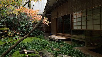 Blick vom zentralen Lichthof auf eine Treppenstufe vor der geöffneten Schiebetür, die in das Tawaraya Ryokan führt